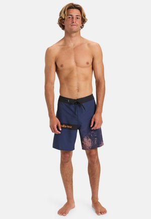Mörkblå badshorts med en gradientdesign, svart midjeband med dragsko och vit logotypdetalj. Tillverkade av lätt material.