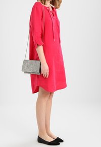 Robe en lin fuchsia à encolure à lacets et manches trois-quarts, associée à un sac bandoulière gris et des ballerines noires.