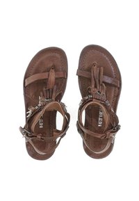 Brune lædersandaler med flad sål, justerbare ankelstropper og dekorative metalaccenter. Tekstureret fodseng med frynse detaljer.