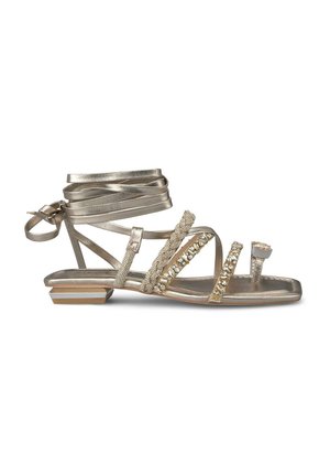 Sandal in metallo dorato con tacco piatto, cinghie decorative, dettagli di perline e lacci alla caviglia. Texture liscia e design aperto davanti.
