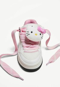 Białe sneakersy z różowymi akcentami i sznurówkami, z pluszową twarzą Hello Kitty przymocowaną do języka. Teksturowana siateczka w górnej części i gumowa podeszwa.