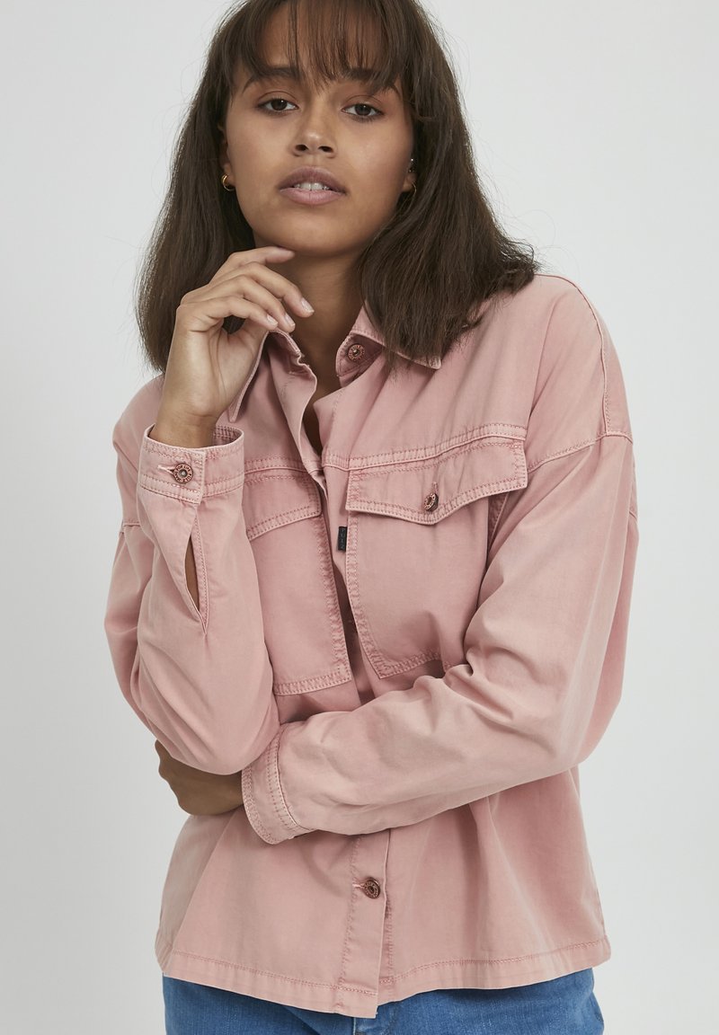 Roze langslavend shirt met knoopsluiting, twee borstzakken en kraag. Gemaakt van textuurstof met een relaxte pasvorm.