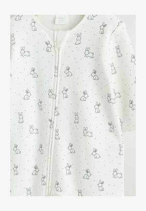 Bijela beba overal s patentnim zatvaračem, ukrašen uzorkom s crnim obrubljenim zečevima i malim crnim točkicama. Glatka pamučna tekstura.