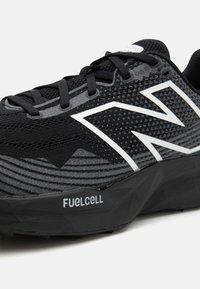 Črne atletske čevlje z mrežasto zgornjico, teksturiranimi sivimi detajli, belimi poudarki in znamko "FUELCELL" na podplatu. Eleganten dizajn in sodobna oblika.