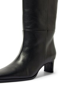 Črni usnjeni škorenj do kolen z teksturirano površino, špičastim vrhom in nizkim blok peto z elegantno in gladko zasnovo.