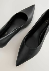 Svarta läderballerinas med spetsig tå, slät textur och låg skärning runt ankeln. Har en enkel, strömlinjeformad design.