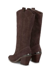 Botas de ante marrón hasta la rodilla con punta curva, costuras decorativas y un tacón de madera grueso con un acento metálico.