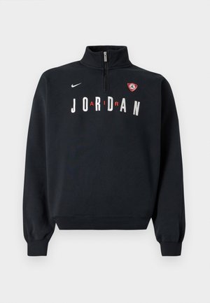 Hanorac negru cu guler înalt, fermoar frontal, text alb „JORDAN” și un patch cu logo pe piept. Material moale și mâneci cu margini ribbed.