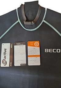 Zwarte neopreen shorty wetsuit met lichtblauwe stiksels, met labels die de materiaalsamenstelling en UV-bescherming van 50+ aan geven.