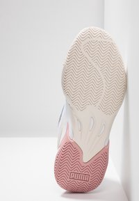 Bílá a růžová podrážka tenisky s vlnitým vzorem, texturovaná guma a výrazně umístěné logo PUMA. Pevný a robustní design.