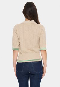 Beige knitted short-sleeve sweater with a ribbed texture and green striped accents at the cuffs and hem. Features a collar and fitted design.