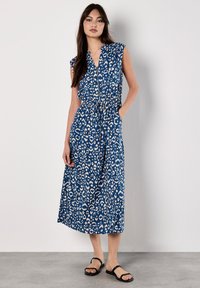 Abito lungo maxi con stampa leopardata blu, scollatura a V, maniche corte e vita elastica. Presenta tasche laterali e un tessuto fluido e texturizzato.