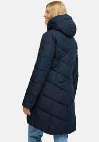 Donkerblauwe pufferjas met capuchon, gekenmerkt door een gewatteerd patroon, zwarte logoaccent en een langere snit die tot halverwege de dij komt.