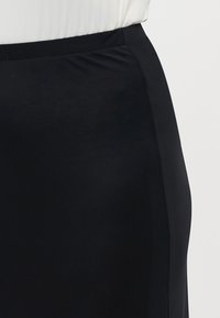 Black pencil skirt made of a smooth, stretchy fabric. Features a fitted shape and a wide waistband for comfort.