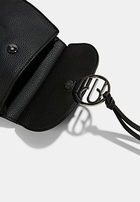 Bolsa de cuero negro texturizado con un cierre metálico redondo, que presenta una correa trenzada y un sutil detalle del logotipo en la parte frontal. Vista abierta.