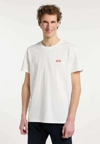 Camiseta de algodón blanca con un pequeño gráfico de una furgoneta vintage roja en el pecho. Mangas cortas y un diseño clásico de cuello redondo.