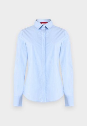 Világoskék hosszú ujjú, gombos ing finom függőleges csíkokkal és hegyes gallérral, egyszínű háttér előtt bemutatva.