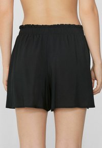 Shorts noirs en tissu léger, dotés d'une taille élastique froncée et d'une coupe ample qui arrive juste au-dessus du genou.