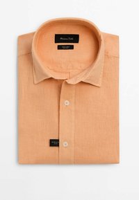Chemise en lin orange clair pliée avec col et deux boutons visibles, étiquetée Massimo Dutti, coupe régulière, 100 % lin.