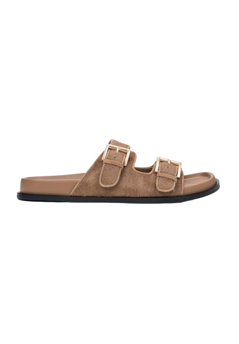 Brown faux fur slide sandals with two adjustable gold buckles, a smooth light brown footbed, and a black rubber sole.
