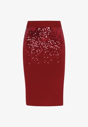 Punainen neulepencil-hame, jossa on ribbitekstuuri ja mustan ja vaaleanpunaisen sävyn gradientti helmassa, luoden säihkypinnan.