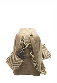 Sac à main en suède beige avec deux zippers dorés, une bandoulière en chaîne et un accent en tissu à motifs. Forme rectangulaire plate avec une texture douce.