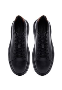 Sneaker in pelle nera con lacci neri e inserti marroni sul tallone, viste dall'alto su uno sfondo bianco.
