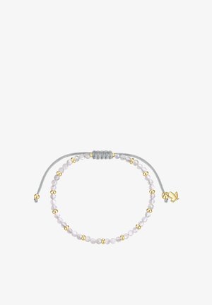 Bracelet ajustable avec des petites perles blanches et dorées alternées sur un cordon gris, avec un charm en forme d’oiseau doré près du nœud.