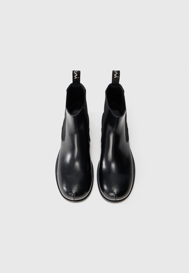Sorte læder ankelstøvler med elastiske sider, rund tå og trækstropper. Glat tekstur og minimalistisk design. Flad gummisål.