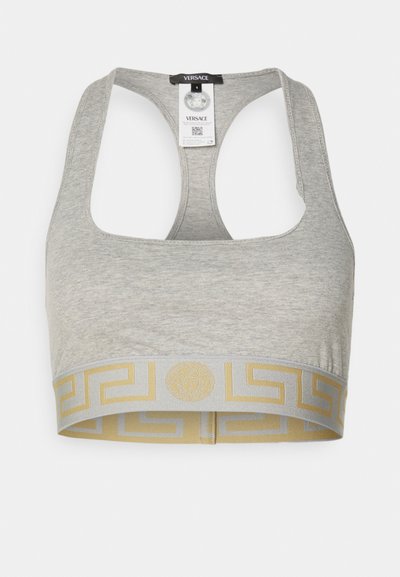 Grau Sport-BH mit einem breiten goldfarbenen und grauen Band, das ein griechisches Schlüsselmotiv und Logodetails aufweist. Das Material wirkt weich und dehnbar.