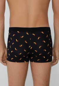 Černé boxerky s opakujícím se vzorem cukrovinek v žluté a červené barvě. Měkká látka s černým elastickým páskem.