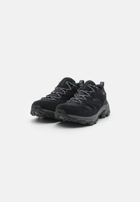 Scarpe da trekking nere con una parte superiore testurizzata, lacci grigi e una suola in gomma resistente, progettate per durabilità e trazione su vari terreni.