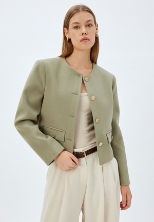 Olive green cropped jacket with four buttons, round neckline, and two front pockets; fabric has a smooth, textured finish.