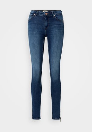 Jean skinny en denim bleu foncé avec une finition délavée, accents zippés aux chevilles, design classique à cinq poches et fermeture à bouton.
