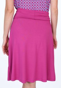 Fuchsiane knielange Rock mit glatter Textur, breitem elastischem Bund und ausgestelltem Saum. Keine sichtbaren Muster oder Akzente.