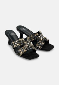 Sandali con tacco in suede nero, caratterizzati da un design con fasce incrociate adornate con decorazioni argento, nero e oro, texture liscia e punta quadrata.