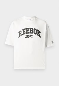 Bijela pamučna majica s kratkim rukavima, s crnim "REEBOK" logotipom i malim Reebok logotipom na lijevom rukavu.