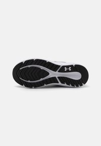 Sorte av atletisk sko i svart og hvitt, med en teksturert, fleksibel gummioverflate og multidireksjonale mønstre. Under Armour-logoen er til stede.