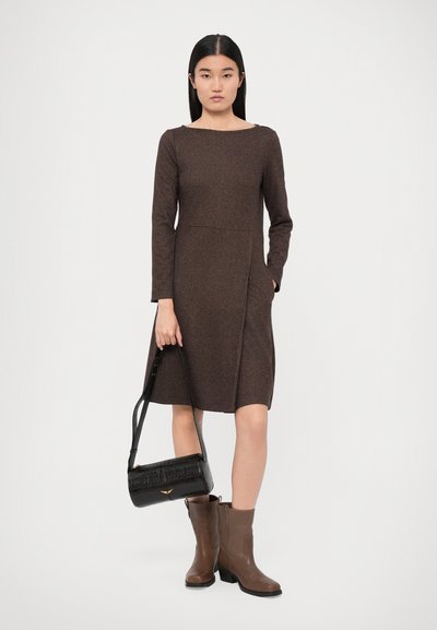 Brown long-sleeve dress with a square neckline, textured fabric, side pockets, and a knee-length hem. Paired with brown ankle boots and a black bag.