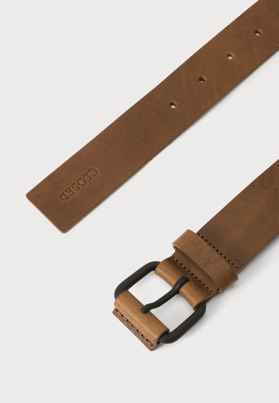 Ceinture en cuir marron avec boucle métallique noire et plusieurs trous d'ajustement, présentant des détails cousus et le nom de la marque embossé sur la lanière.