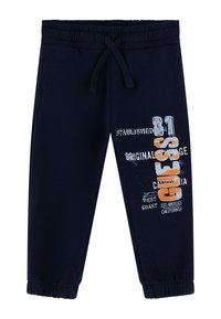 Pantalones de chándal azul marino con cintura elástica y cordón, con un diseño gráfico en blanco y naranja en la pierna izquierda.