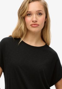 Zwarte t-shirt met korte mouwen en ronde hals, gemaakt van een zachte, lichtgewicht stof, met een relaxte pasvorm en subtiele textuur.