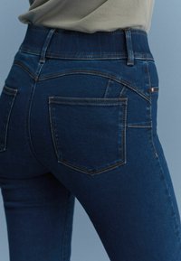 Donkerblauwe denim jeans met een strakke pasvorm, voorzien van twee achterzakken met contrasterende stiksels en een hoge tailleband.