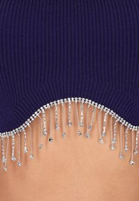 Paars geribbeld crop-top met een geschulpte zoom, versierd met zilveren kralenfranje voor extra textuur en detail.