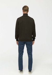 Sötétbarna pulóver magas gallérral, kék nadrággal és szürke sportcipővel viselve, egyszerű kötött textúrával és laza dizájnnal.