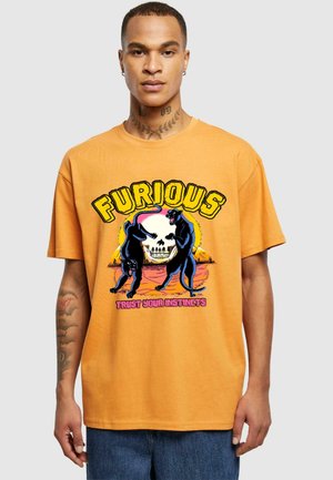 Orange bomulds t-shirt med grafik af to sorte pantere og et kranium, med "FURIOUS" og "TRUST YOUR INSTINCTS" i fed skrift.
