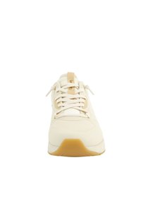 Forfra af en beige sneaker med hvide snørebånd og en lys brun gummisål på en hvid baggrund.
