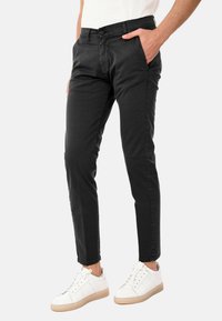 Chinos neri in cotone con vestibilità slim, tasche anteriori e chiusura con bottone. Indossati con sneaker bianche e una t-shirt semplice.