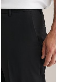 Svarta skräddarsydda byxor med en mjuk tygtextur, rak skärning, sidofickor och en smal midjeband.