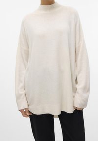 Pull en tricot crème surdimensionné avec col, poignets et ourlet côtelés, porté avec un pantalon noir, présenté sur une personne de la nuque aux hanches.